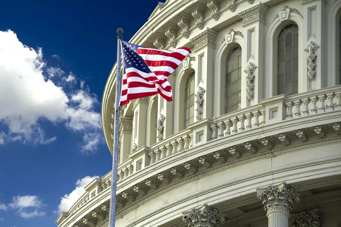 American flag flying outside a historic government building representing PE/360 property insurance solutions for municipalities, hospitals, and nonprofit organizations.